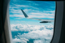 Airplane wing above the clouds as seen from an airplane window